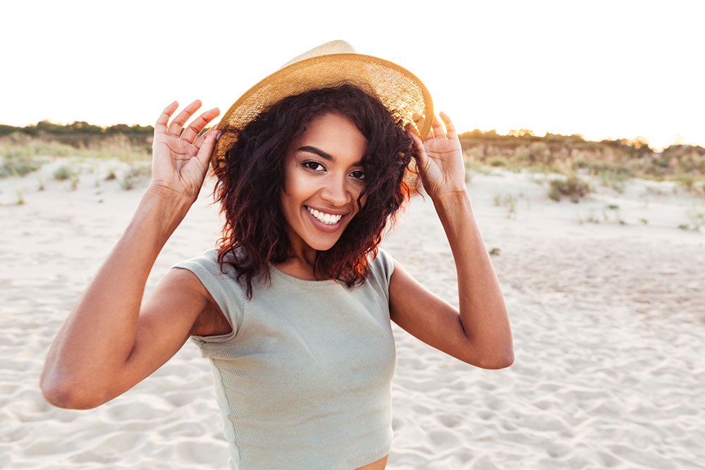 beautiful woman holding a hat smiling