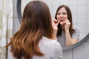 woman in front of mirror putting in aligners